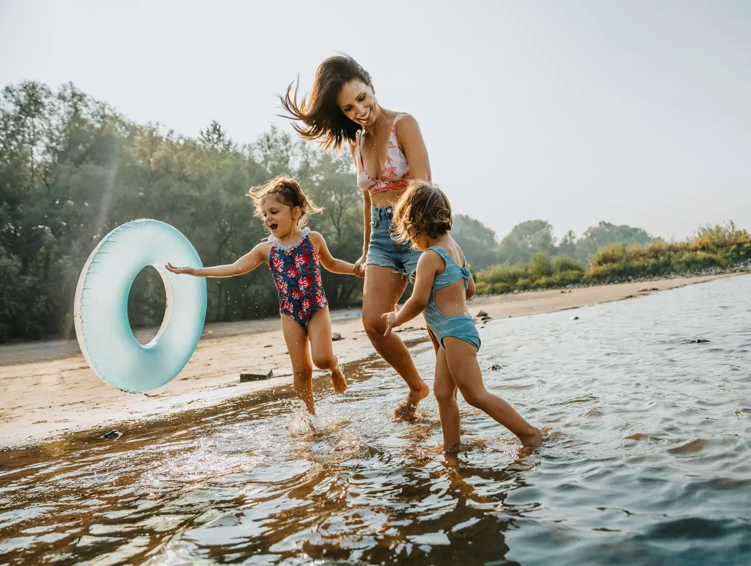 Mãe e crianças em praia fluvial durante umas férias económicas em família.