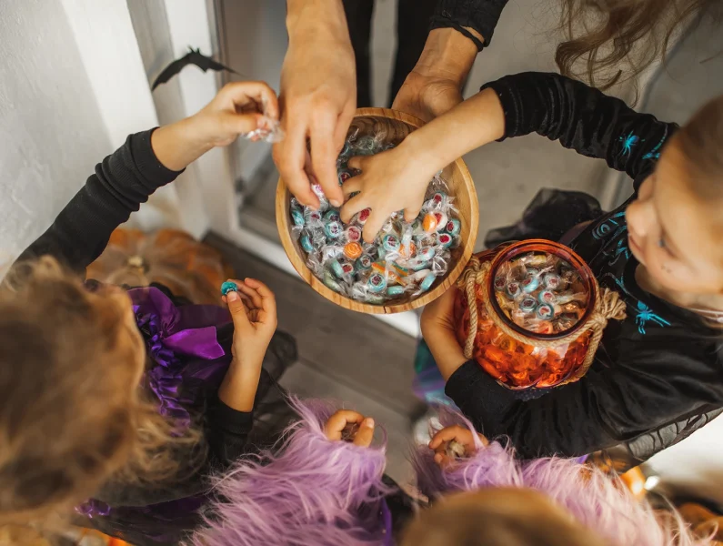 Crianças em fantasia de Halloween infantil a pedir doces na rua, seguindo a tradição do doce ou travessura.