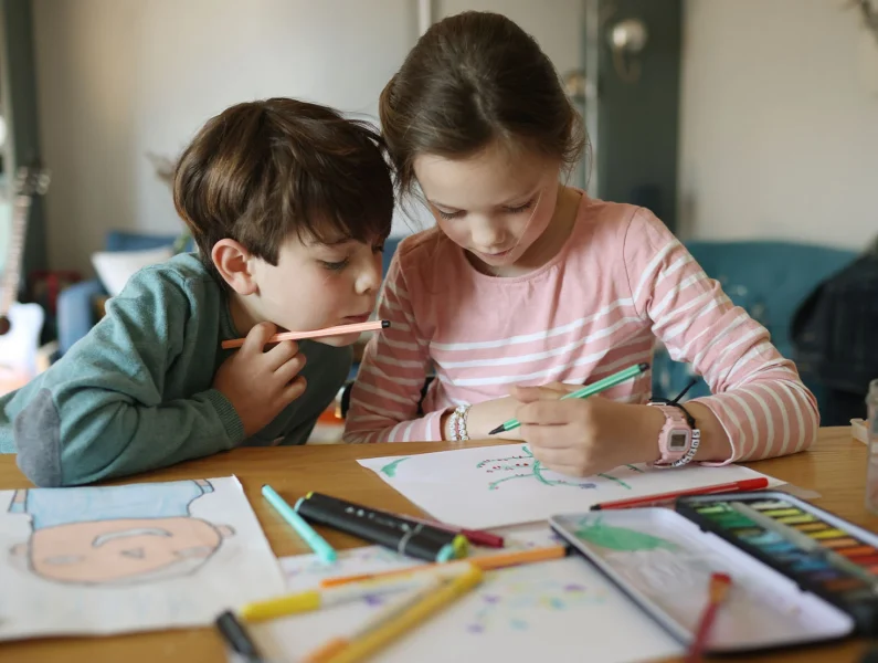 Duas crianças a colorir desenhos infantis 