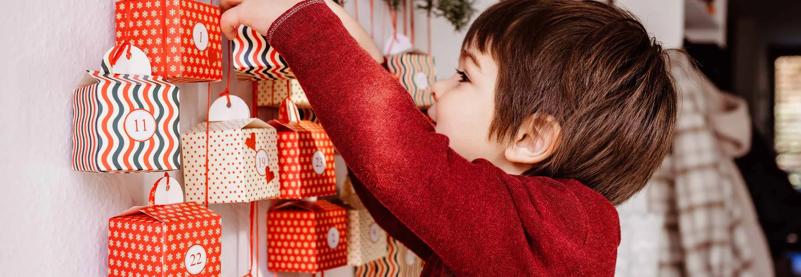 Criança a abrir Calendário de advento de parede.