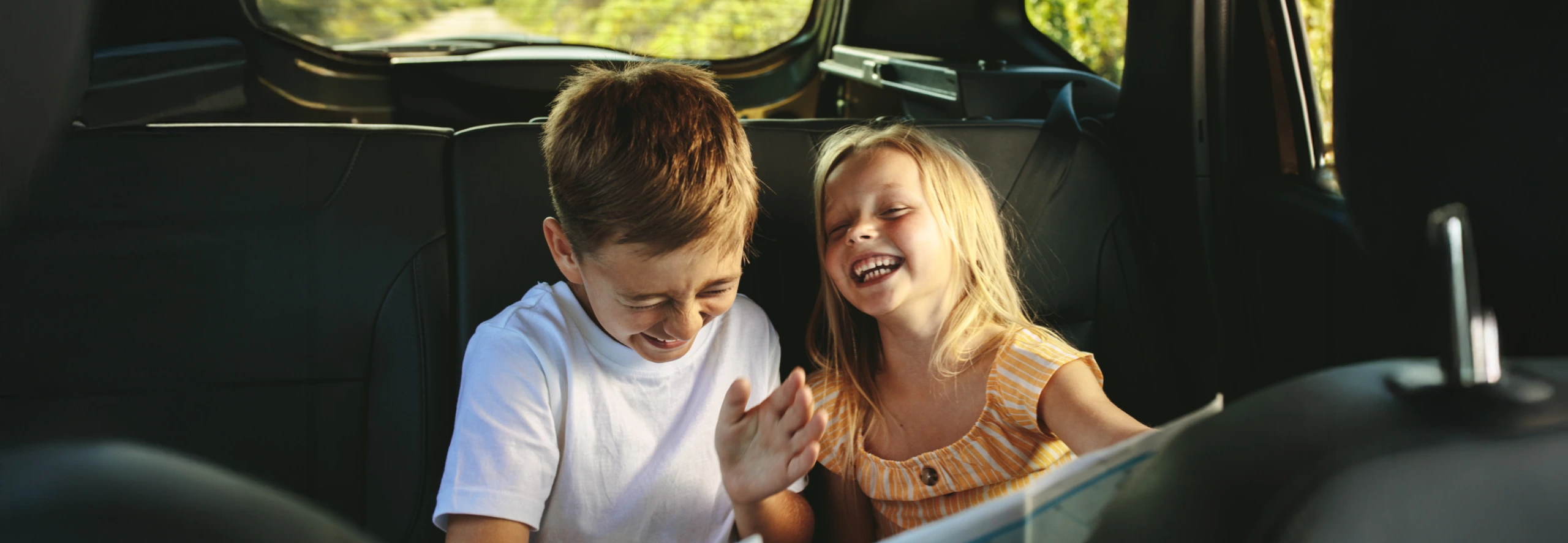 crianças a rir enquanto jogam no carro