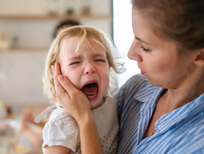 Criança no colo da mãe a fazer birra