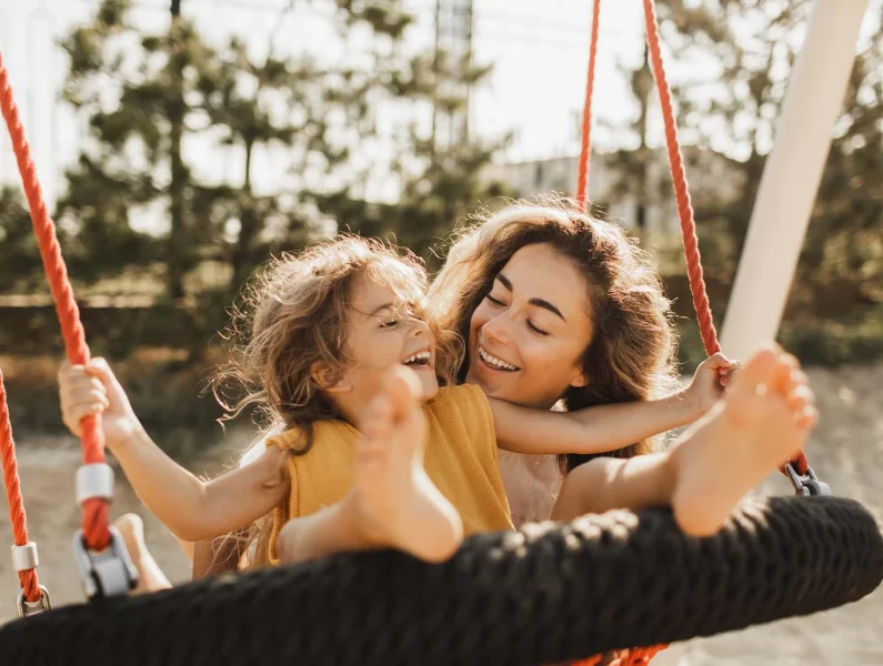 Criança e mãe a brincar num parque durante atividades de verão em família